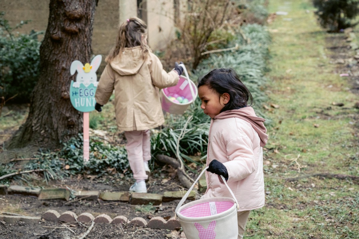 Twee kinderen zoeken eieren tussen het groen.